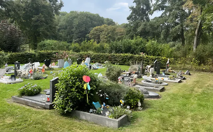 669776e9b7f3723e29c50cf5 De begraafplaats in Almere stad met enkele graven en bloemstukken van nabestaanden - Noach Uitvaartzorg